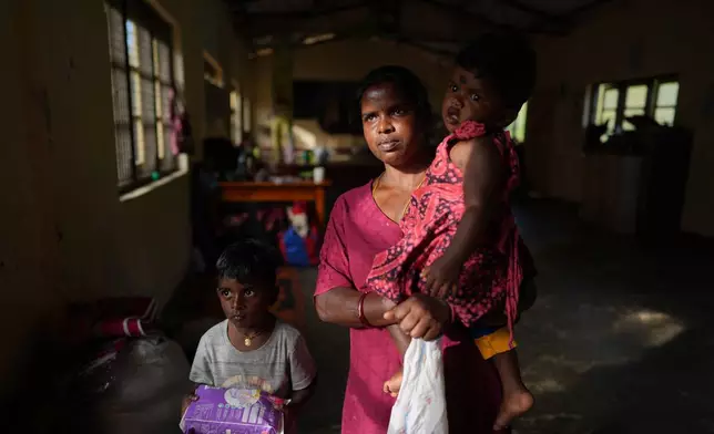 Sellamuttu Darshani Devi, a tea plantation worker evacuated after Cyclone Ditwah led to floods and landslides, shelters with her children at a safety center in Galamuduna Estate in Dolosbage, Sri Lanka, Friday, Dec.12, 2025. (AP Photo/Eranga Jayawardena)