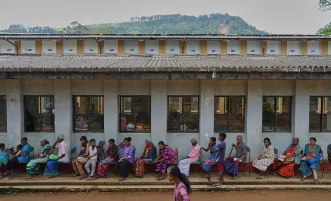 Displaced tea plantation workers and their families queue for aid at a safety center after Cyclone Ditwah led to floods and landslides at Craighead Estate in Nawalapitiya, Sri Lanka, Friday, Dec.12, 2025. (AP Photo/Eranga Jayawardena)