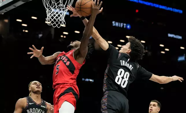 Brooklyn Nets guard Nolan Traore (88) blocks Toronto Raptors guard Immanuel Quickley (5) during the first half of an NBA basketball game, Sunday, Dec. 21, 2025, in New York. (AP Photo/Yuki Iwamura)
