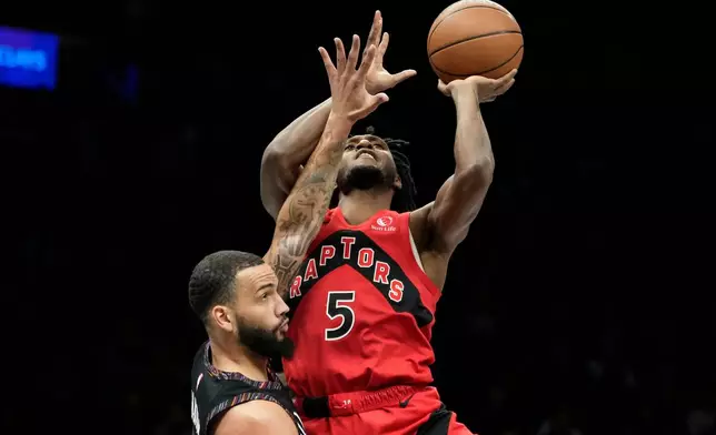 Toronto Raptors guard Immanuel Quickley (5) looks to shoot over Brooklyn Nets guard Tyrese Martin during the first half of an NBA basketball game, Sunday, Dec. 21, 2025, in New York. (AP Photo/Yuki Iwamura)