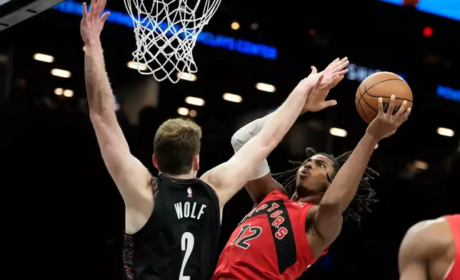 Toronto Raptors forward Collin Murray-Boyles (12) looks to shoot over Brooklyn Nets forward Danny Wolf (2) during the first half of an NBA basketball game, Sunday, Dec. 21, 2025, in New York. (AP Photo/Yuki Iwamura)
