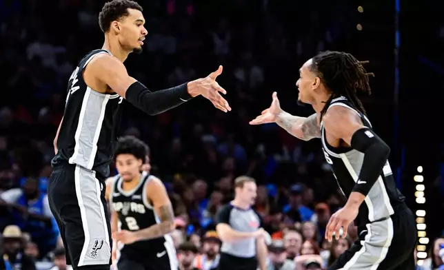 San Antonio Spurs forward/center Victor Wembanyama (1) celebrates with San Antonio Spurs guard/forward Devin Vassell (24) during the second half of an NBA basketball game, Thursday, Dec. 25, 2025, in Oklahoma City. (AP Photo/Gerald Leong)