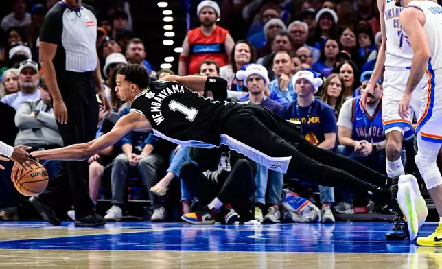 San Antonio Spurs forward/center Victor Wembanyama (1) goes for the free ball against the Oklahoma City Thunder during the second half of an NBA basketball game, Thursday, Dec. 25, 2025, in Oklahoma City. (AP Photo/Gerald Leong)