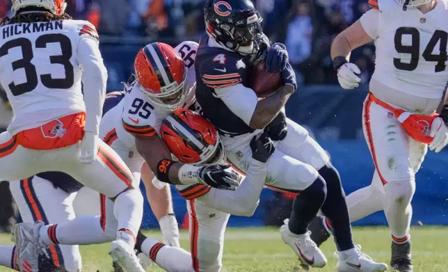Chicago Bears running back D'Andre Swift (4) is tackled by Cleveland Browns linebacker Mohamoud Diabate (43) and defensive end Myles Garrett (95) in the first half of an NFL football game in Chicago, Sunday, Dec. 14, 2025. (AP Photo/Nam Y. Huh)