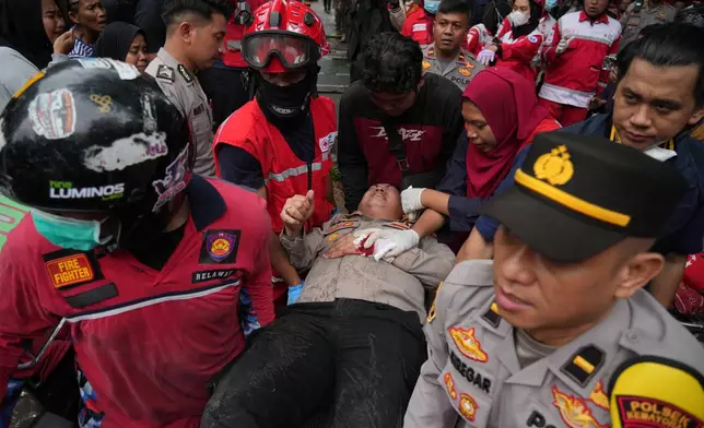 Rescuers tend to an injured police officer at the site of a fire in Jakarta, Indonesia, Tuesday, Dec. 9, 2025. (AP Photo/Dita Alangkara)