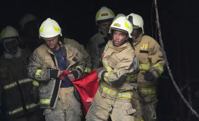 Rescuers carry out the body of a victim from the site of a fire in Jakarta, Indonesia, Tuesday, Dec. 9, 2025. (AP Photo/Dita Alangkara)