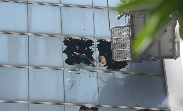 A firefighter breaks glass in an office building that caught fire in Jakarta, Indonesia, Tuesday, Dec. 9, 2025. (AP Photo/Dita Alangkara)