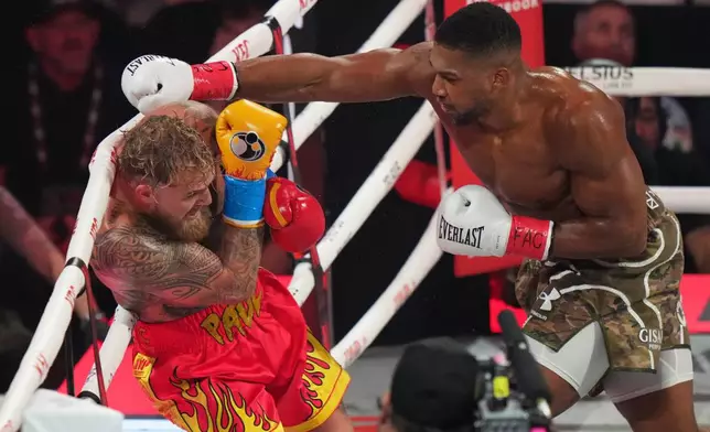 Anthony Joshua, right, punches Jake Paul during their heavyweight boxing match, Friday, Dec. 19, 2025, in Miami, Fla. (AP Photo/Lynne Sladky)