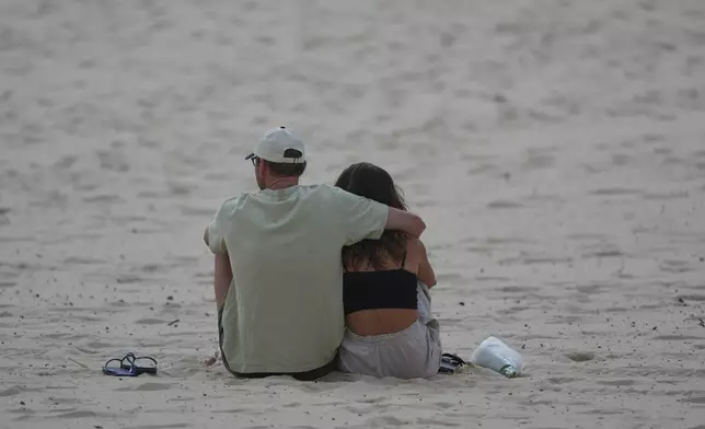A couple embrace a day after a shooting at Sydney's Bondi Beach, Monday, Dec. 15, 2025. (AP Photo/Mark Baker)