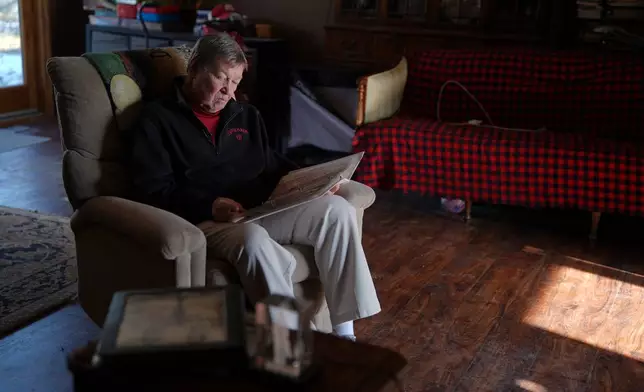 Bill Murphy, 77, an Indiana football fan, looks through vintage sports programs in a photo album at his home in Greenfield, Ind., Wednesday Dec. 17, 2025. (AP Photo/Obed Lamy)