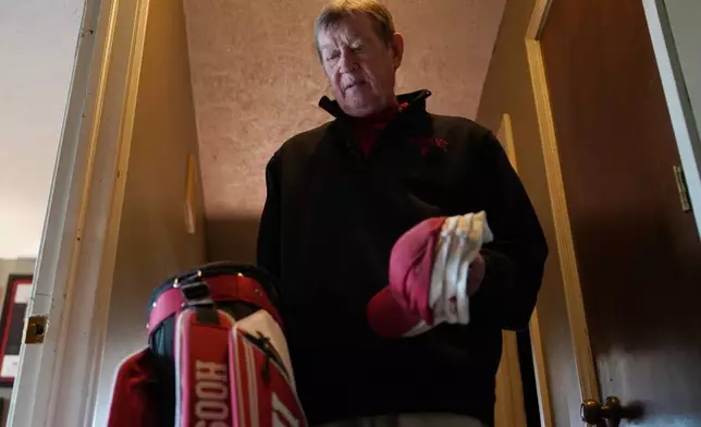 Bill Murphy, 77, an Indiana football fan, walks through the hallway of his home in Greenfield, Ind., carrying sports hats and a golf bag Wednesday Dec. 17, 2025. (AP Photo/Obed Lamy)