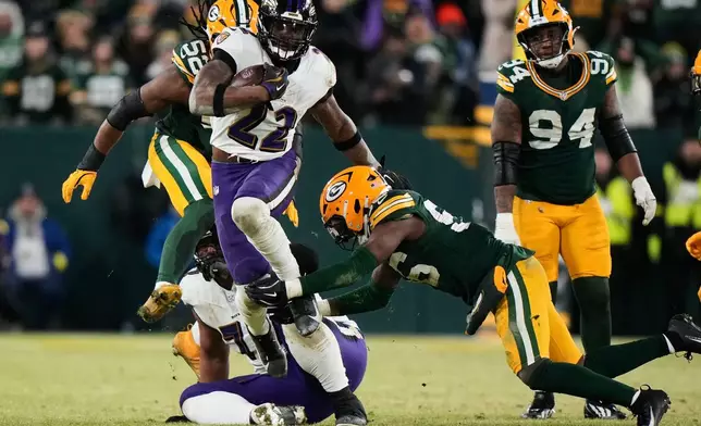Baltimore Ravens running back Derrick Henry (22) runs the ball past Green Bay Packers linebacker Edgerrin Cooper (56) and defensive end Rashan Gary (52) during the second half of an NFL football game, Saturday, Dec. 27, 2025, in Green Bay, Wis. (AP Photo/Morry Gash)