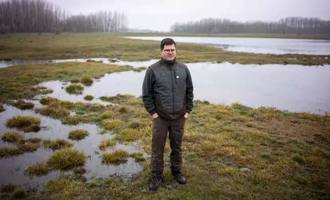 Oszkár Nagyapáti, farmer and member of the volunteer water guardians group, poses for a photo with an artificial lake in Kiskunmajsa, Hungary, Tuesday, July 29, 2025. (AP Photo/Denes Erdos)