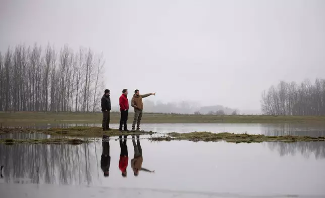 Members of the water guardians group talk next to an artificial lake in Kiskunmajsa, Hungary, Friday, Dec. 12, 2025. (AP Photo/Denes Erdos)