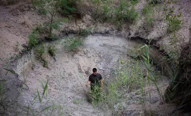 Oszkár Nagyapáti, farmer and member of the volunteer water guardians, stands in a hole in Kiskunmajsa, Hungary, Tuesday, July 29, 2025. (AP Photo/Denes Erdos)