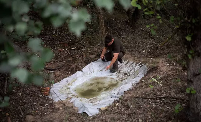 Oszkár Nagyapáti, farmer and member of the volunteer water guardians group, fills up a wildlife water trough in Kiskunmajsa, Hungary, Tuesday, July 29, 2025. (AP Photo/Denes Erdos)