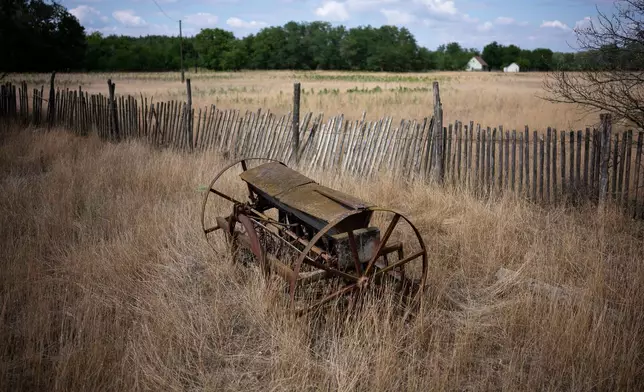 An abandoned plow sits on parched land in Kiskunmajsa, Hungary, Monday, July 28, 2025. (AP Photo/Denes Erdos)