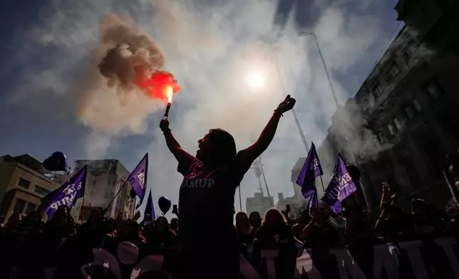 A woman waves a flare during a march marking International Women's Day in Santiago, Chile, March 8, 2025. (AP Photo/Esteban Felix, File)