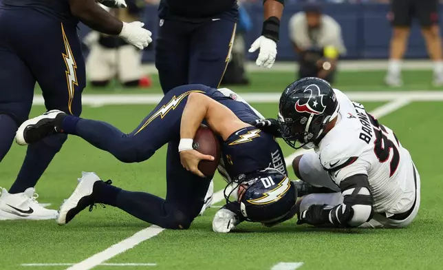 Los Angeles Chargers quarterback Justin Herbert (10) is sacked by Houston Texans defensive end Derek Barnett (95) during the second half of an NFL football game Saturday, Dec. 27, 2025, in Inglewood, Calif. (AP Photo/Kevork Djansezian)