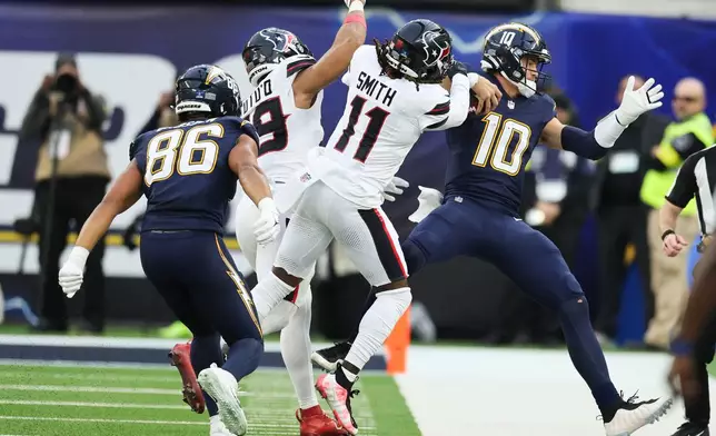 Los Angeles Chargers quarterback Justin Herbert (10) is forced out of bounds by Houston Texans linebacker Henry To'Oto'O (39) and cornerback Tremon Smith (11) during the first half of an NFL football game Saturday, Dec. 27, 2025, in Inglewood, Calif. (AP Photo/Kevork Djansezian)