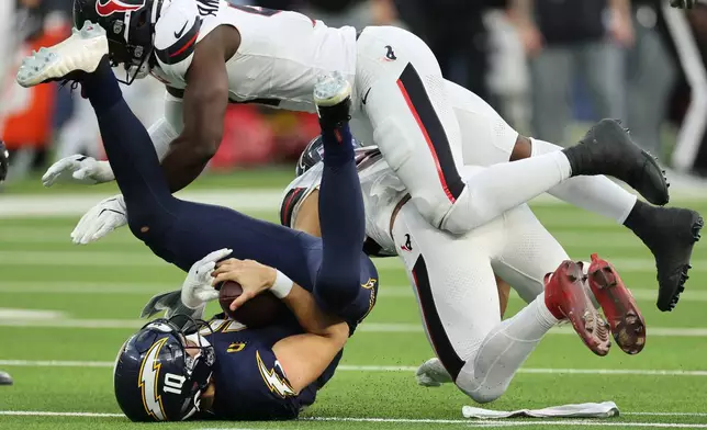 Los Angeles Chargers quarterback Justin Herbert, bottom left, is sacked by Houston Texans linebacker Henry To'Oto'O during the second half of an NFL football game Saturday, Dec. 27, 2025, in Inglewood, Calif. (AP Photo/Kevork Djansezian)
