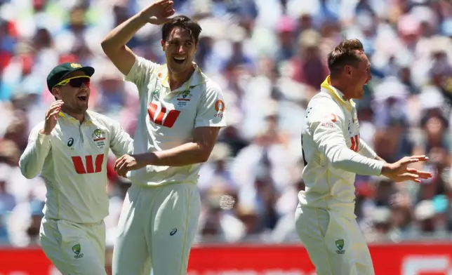 Australia's Pat Cummins, centre, celebrates with teammate Australia's Marnus Labuschagne, right, after dismissing England's Ollie Pope during play on day four of the third Ashes cricket test between England and Australia in Adelaide, Australia, Saturday, Dec. 20, 2025. (AP Photo/James Elsby)