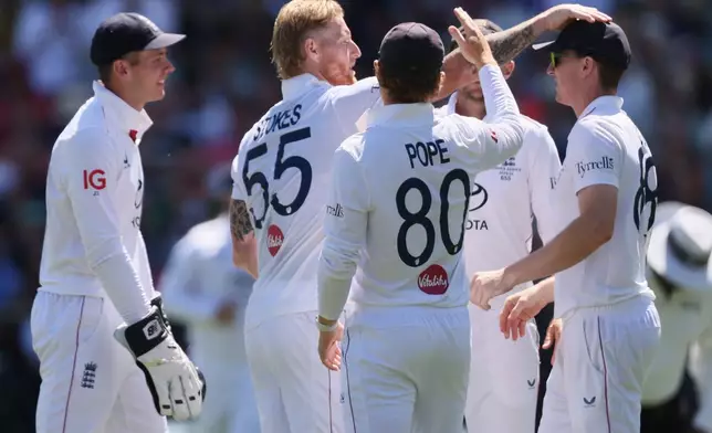 England's Ben Stokes, centre, celebrates with teammates after dismissing Australia's Alex Carey during play on day four of the third Ashes cricket test between England and Australia in Adelaide, Australia, Saturday, Dec. 20, 2025. (AP Photo/James Elsby)
