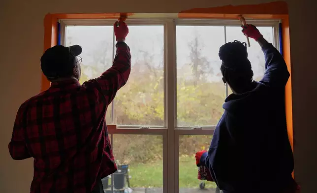 A group from the Neighborhood Resilience Project, an Orthodox social service agency connected to St. Moses the Black Orthodox Church, paints a home in Clairton, Pa., as part of the organization's community-building programs, Monday, Nov. 24, 2025. (AP Photo/Jessie Wardarski)