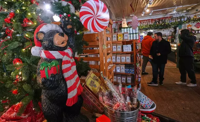 Post-holiday shoppers pass a Christmas tree and festive display at Calef's Country Store, Friday, Dec. 26, 2025, in Barrington, N.H. (AP Photo/Charles Krupa)