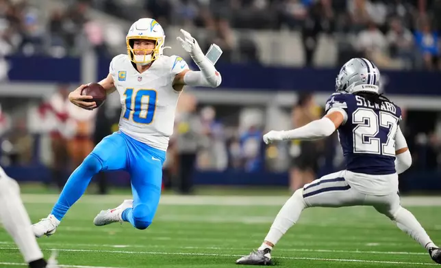 Los Angeles Chargers quarterback Justin Herbert (10) slides during the second half of an NFL football game against the Dallas Cowboys, Sunday, Dec. 21, 2025, in Arlington, Texas. (AP Photo/Tony Gutierrez)
