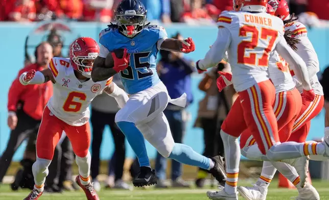 Tennessee Titans tight end Chig Okonkwo (85) runs for a first down between Kansas City Chiefs safety Bryan Cook (6) and safety Chamarri Conner (27) during the first half of an NFL football game Sunday, Dec. 21, 2025, in Nashville, Tenn. (AP Photo/George Walker IV)
