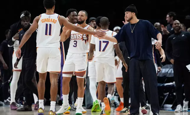 Phoenix Suns forward Oso Ighodaro (11) high-fives guard Devin Booker, right, during the second half of an NBA basketball game against the Minnesota Timberwolves, Monday, Dec. 8, 2025, in Minneapolis. (AP Photo/Abbie Parr)