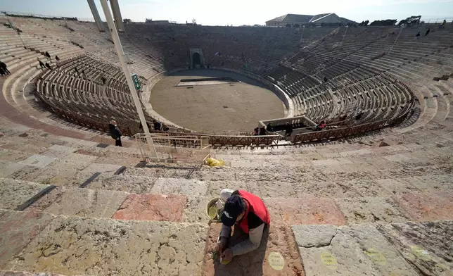 A worker removes seat number stickers used to mark places during concerts at the Arena of Verona, Italy, Wednesday, Dec. 10, 2025. (AP Photo/Luca Bruno)