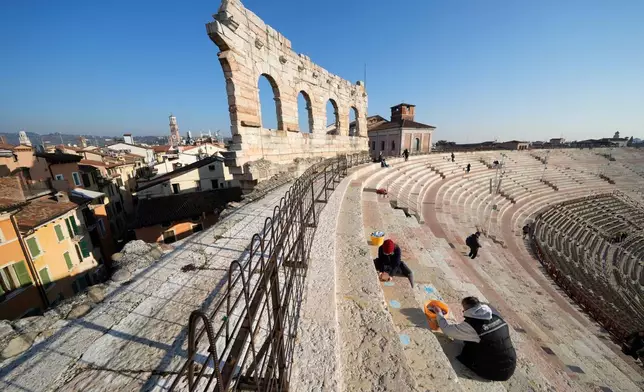 A worker removes seat number stickers used to mark places during concerts at the Arena of Verona, Italy, Wednesday, Dec. 10, 2025. (AP Photo/Luca Bruno)
