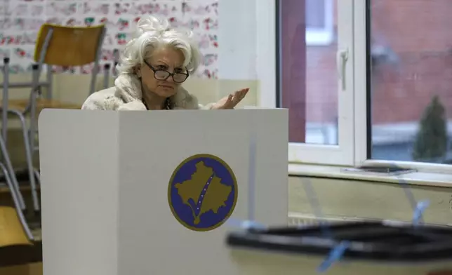A voter prepares her ballot at a polling station in an early parliamentary election in the northern Serb-dominated part of ethnically divided town of Mitrovica, Kosovo, Sunday, Dec. 28, 2025. (AP Photo/Bojan Slavkovic)