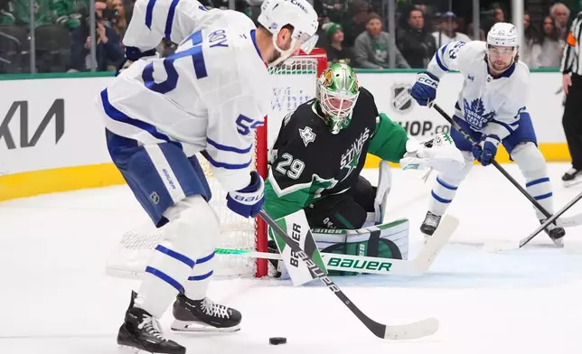 Dallas Stars goaltender Jake Oettinger (29) defends the goal against Toronto Maple Leafs center Nicolas Roy (55) and left wing Matias MacCelli (63) during the second period of an NHL hockey game Sunday, Dec. 21, 2025, in Dallas. (AP Photo/LM Otero)