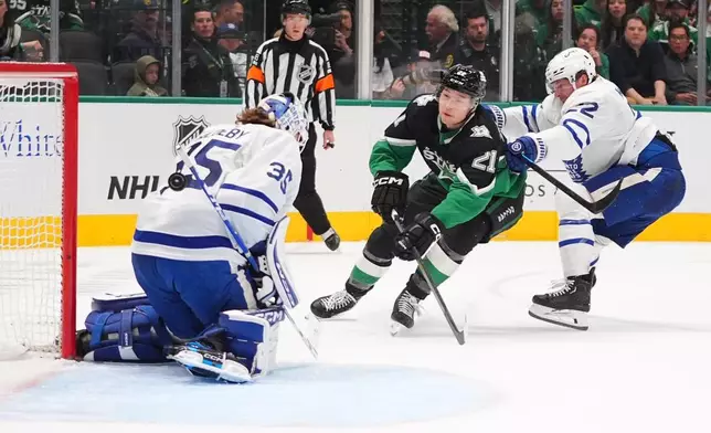 Dallas Stars left wing Jason Robertson (21) scores against Toronto Maple Leafs goaltender Dennis Hildeby (35) and defenseman Jake McCabe (22) during the first period of an NHL hockey game Sunday, Dec. 21, 2025, in Dallas. (AP Photo/LM Otero)