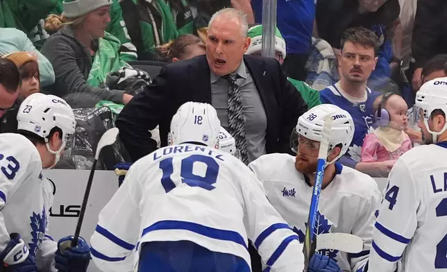 Toronto Maple Leafs head coach Craig Berube, center top, speaks to the bench during the second period of an NHL hockey game against the Dallas Stars, Sunday, Dec. 21, 2025, in Dallas. (AP Photo/LM Otero)