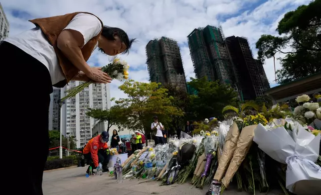 A woman bows as she offers flowers near the site of a deadly fire at Wang Fuk Court, a residential estate in the Tai Po district of Hong Kong's New Territories on Tuesday, Dec. 2, 2025. (AP Photo/Ng Han Guan)
