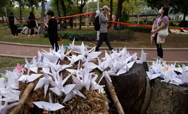 People pass near paper cranes placed near the site of a deadly fire at Wang Fuk Court, a residential estate in the Tai Po district of Hong Kong's New Territories on Tuesday, Dec. 2, 2025. (AP Photo/Ng Han Guan)