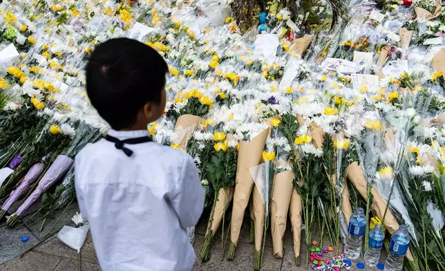 People offer flowers for the victims near the site of a deadly fire at Wang Fuk Court, a residential estate in the Tai Po district of Hong Kong's New Territories on Tuesday, Dec 2, 2025. (AP Photo/Chan Long Hei)