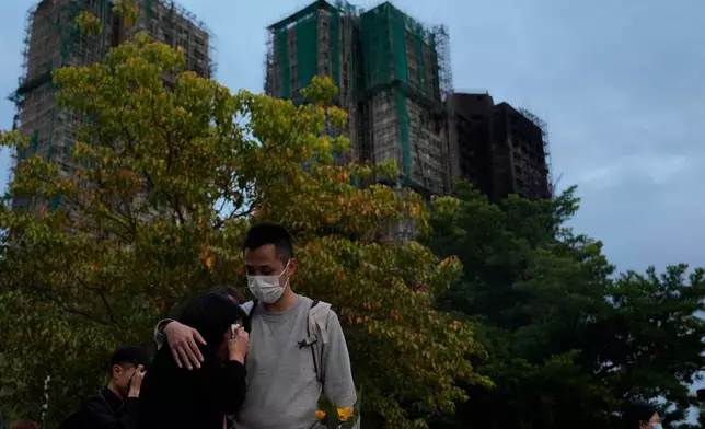 A man consoles a woman at the site of last weeks deadly fire at Wang Fuk Court, a residential estate in the Tai Po district of Hong Kong's New Territories on Tuesday, Dec. 2, 2025. (AP Photo/Ng Han Guan)