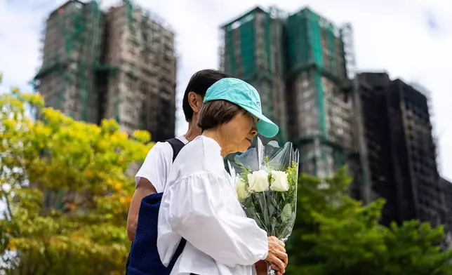 People offer flowers for the victims near the site of a deadly fire at Wang Fuk Court, a residential estate in the Tai Po district of Hong Kong's New Territories on Tuesday, Dec 2, 2025. (AP Photo/Chan Long Hei)