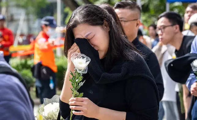 People react as they offer flowers for the victims near the site of a deadly fire at Wang Fuk Court, a residential estate in the Tai Po district of Hong Kong's New Territories on Tuesday, Dec 2, 2025. (AP Photo/Chan Long Hei)