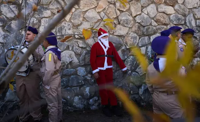 A youth wears a Santa Claus costume as he waits alongside Boy Scouts to take part in the 40th annual Christmas parade in Nazareth, Israel, Wednesday, Dec. 24, 2025. (AP Photo/Ariel Schalit)
