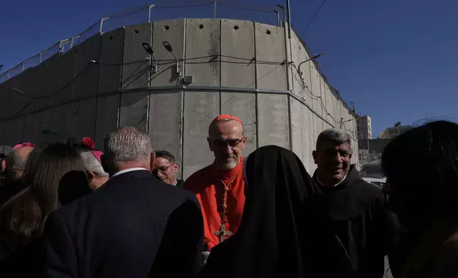 Latin Patriarch Pierbattista Pizzaballa, the top Catholic clergyman in the Holy Land, is received by local community while crossing an Israeli military checkpoint from Jerusalem ahead of celebrations at the Church of the Nativity, traditionally believed to be the birthplace of Jesus, on Christmas Eve, in the West Bank city of Bethlehem, Wednesday, Dec. 24, 2025. (AP Photo/Mahmoud Illean)