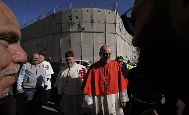 Latin Patriarch Pierbattista Pizzaballa, the top Catholic clergyman in the Holy Land, is received by local community while crossing an Israeli military checkpoint from Jerusalem ahead of celebrations at the Church of the Nativity, traditionally believed to be the birthplace of Jesus, on Christmas Eve, in the West Bank city of Bethlehem, Wednesday, Dec. 24, 2025. (AP Photo/Mahmoud Illean)
