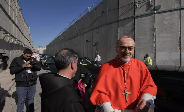 Latin Patriarch Pierbattista Pizzaballa, the top Catholic clergyman in the Holy Land, is received by local community while crossing an Israeli military checkpoint from Jerusalem ahead of celebrations at the Church of the Nativity, traditionally believed to be the birthplace of Jesus, on Christmas Eve, in the West Bank city of Bethlehem, Wednesday, Dec. 24, 2025. (AP Photo/Mahmoud Illean)