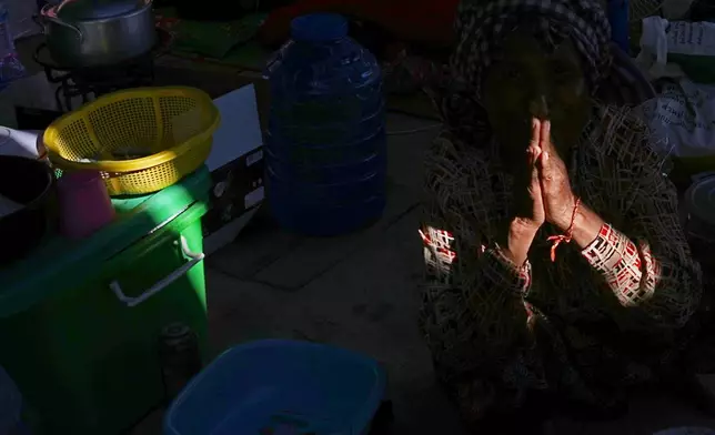 A displaced people prays as she takes their refuge in Prey Chamkar Ta Doak market in Banteay Meanchey province, Monday, Dec. 15, 2025, after fleeing home following fighting along the Thailand-Cambodia border. (AP Photo/Heng Sinith)