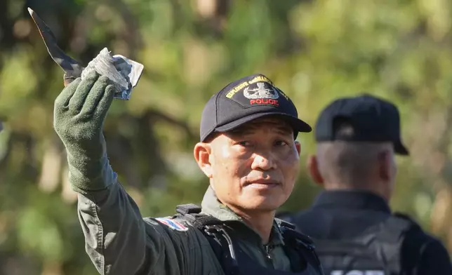 A member of a Thai Explosive Ordnance Disposal team shows pieces of shrapnel as they inspect the site of a rocket attack during clashes between Thai and Cambodian soldiers in Kantharalak district of Sisaket province, Thailand, Monday, Dec. 15, 2025. (AP Photo/Sakchai Lalit)